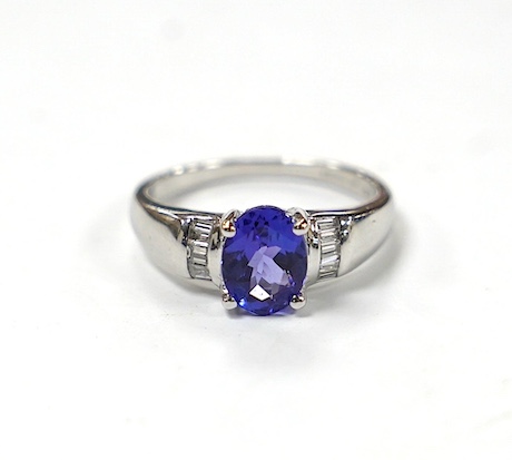 A modern 18ct gold and single stone oval cut tanzanite set ring, with baguette cut diamond cluster set shoulders, with accompanying AnchorCert report, stating the stone to weigh 1.20ct, size L, gross weight 4.1 grams. Co